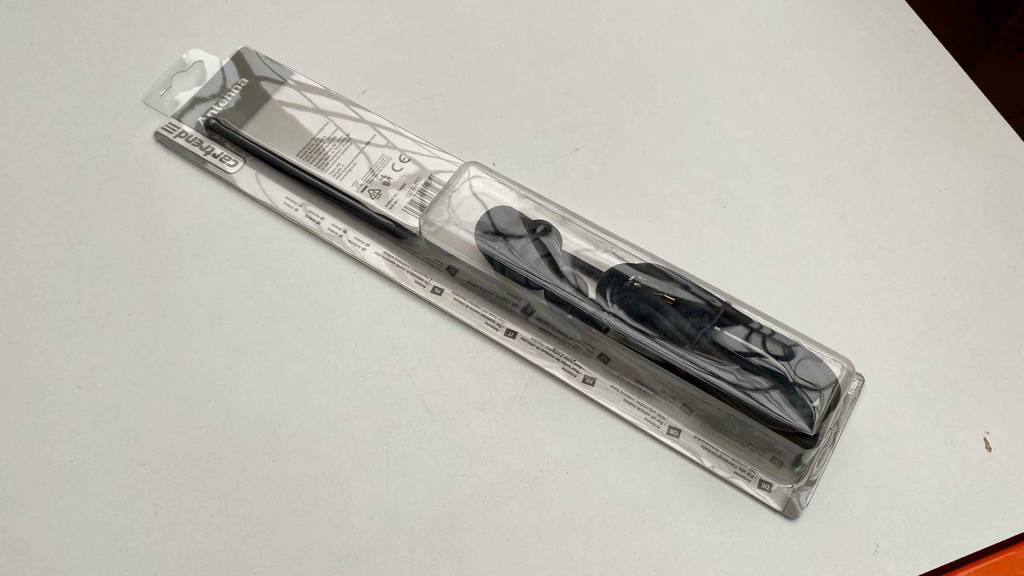 Autoantennen im Test: ein in der transparenten Originalverpackung eingeschweißte schwarze Autoantenne liegt auf einer weißen Fläche.