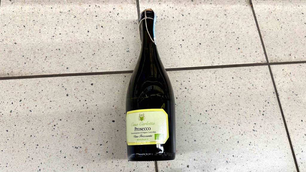 Bio-Wein-Test: Eine bauchige Flasche mit Prosecco liegt auf dem Boden.
