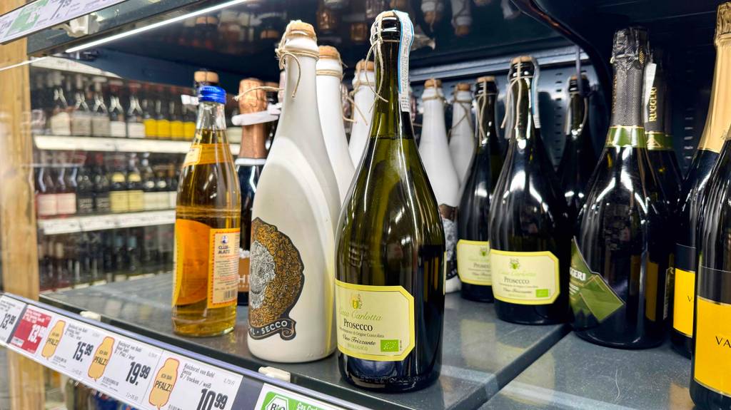 Bio-Wein im Test: Eine bauchige Flasche mit Prosecco steht neben weiteren Weinsorten auf einem Verkaufsregal.