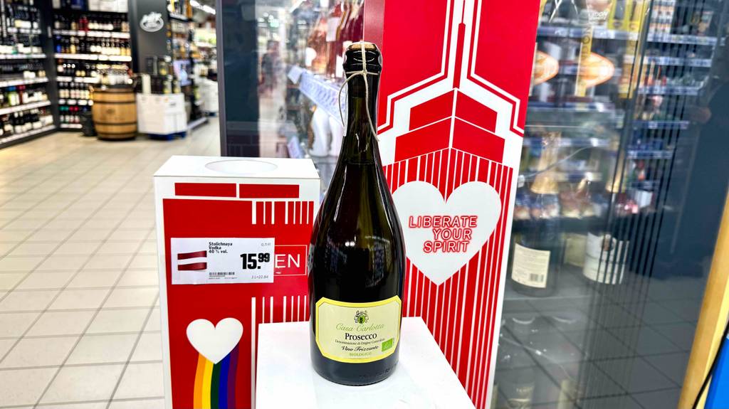 Getesteter Bio-Wein in der bauchigen Prosecco-Flasche inklusive Korkenverschluss steht auf einem Podest im Supermarkt.