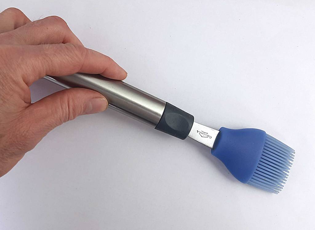 Grillpinsel-Test: Eine Hand hält einen Grillpinsel, mit violettfarbenem Silikon-Kopf, am Aluminium-Griff.