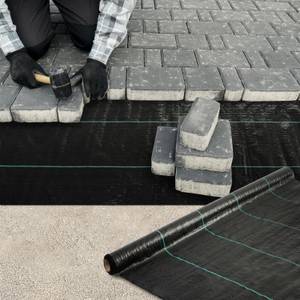Unkrautvlies im Test: Schwarzes Unkrautvlies unter Pflastersteinen, die verlegt werden.
