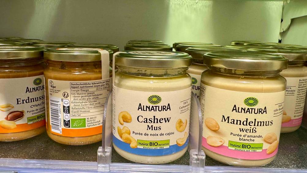 Mehrere Gläser des getesteten Cashewmus in einem Regal neben anderen Produkten.