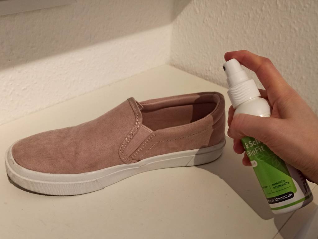 Ein Schuhdeo neben einem Schuh, in den es gesprüht werden soll.