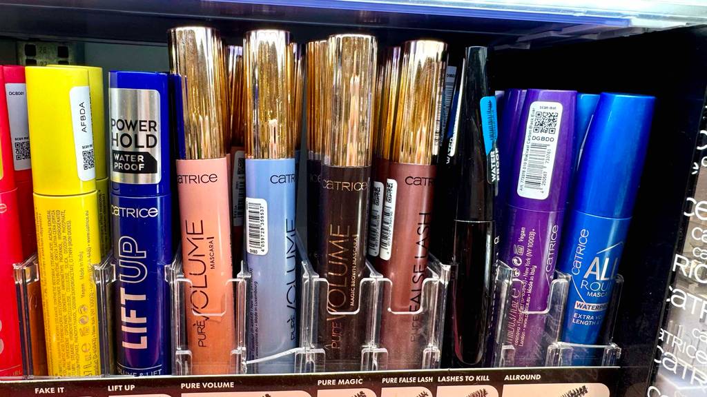 Mascara braun im Test: Mehrere Flakons stehen zwischen anderen Farben in einem Regal.