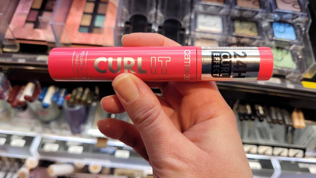 Eine Hand hält eine rote Catrice-Mascara zum testen.
