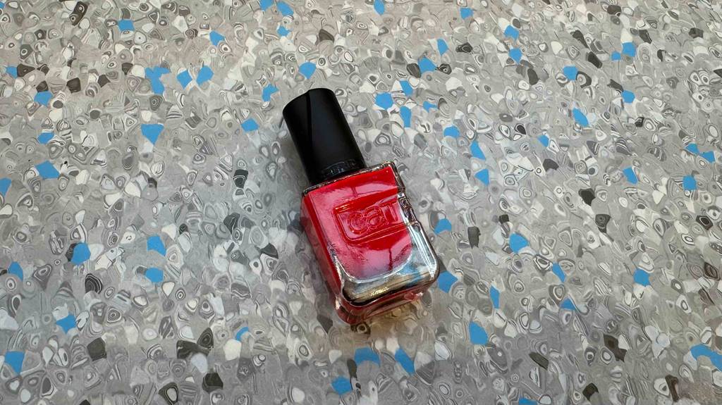 Im Test: Roter Nagellack liegt auf einem Linoleumbelag.
