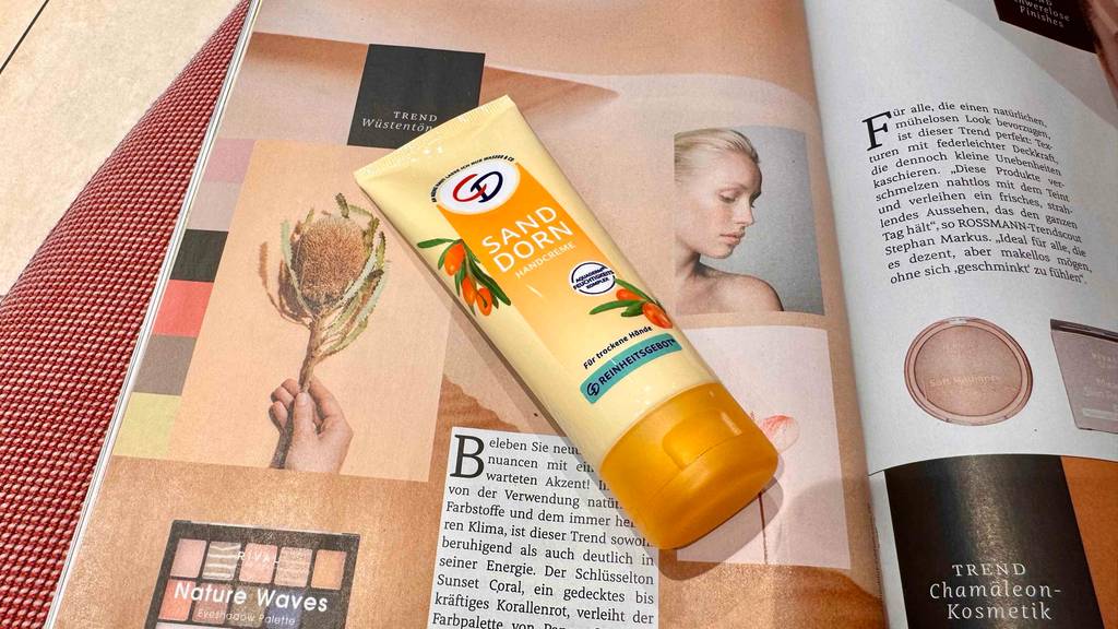 Eine Tube getestete Sanddorn-Handcreme liegt auf einer Seite einer aufgeschlagenen Zeitschrift.