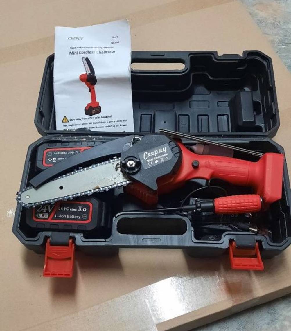 Mini-Kettensäge im Test: ein schwarz-rotes Modell der Marke Ceepuy liegt in seinem schwarzen, geöffneten Transportkoffer inklusive Akku sowie Schraubendreher und Bedienungsanleitung.