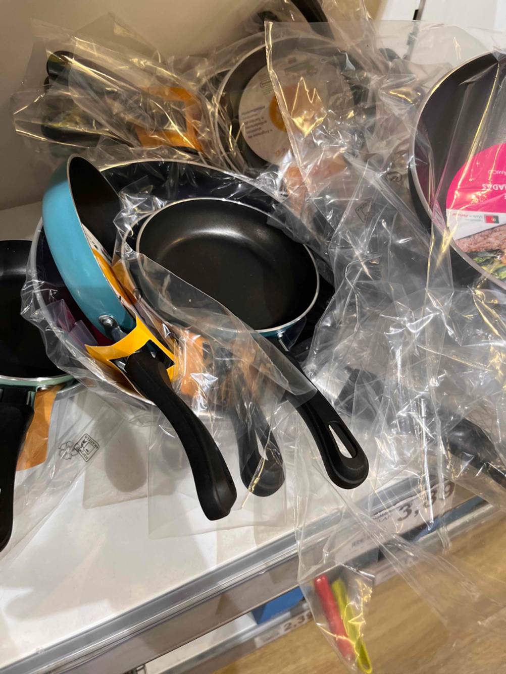 Türkisfarbige Spiegeleipfanne im Test befindet sich inmitten verschiedenster Pfannen im Verkaufsregal.