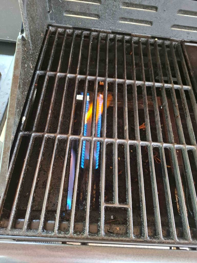 Gasgrill bis 300 Euro im Test: Blick auf den Rost über der brennenden Gasflamme.