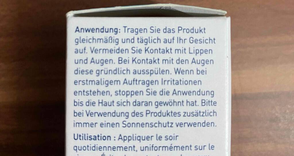 Retinol-Serum im Test: eine weiße Verpackung mit Anwendungsbeschreibung vor einem Holzhintergrund.