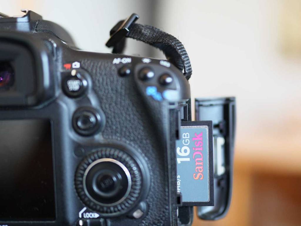 CF-Karten im Test: Detailansicht einer SanDisk 16 GB Karte, halb eingesteckt im geöffneten Fach einer Digitalkamera.
