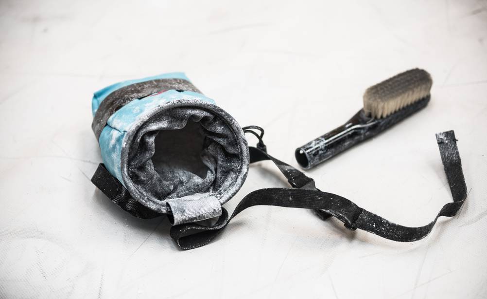 Chalkbag-Test: Eine blaue Chalkbag mit Gurt liegt auf dem Boden. Daneben liegt eine Bürste. 