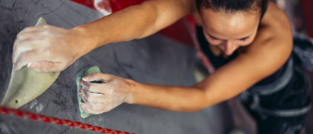 Chalkbag-Test: Eine Frau klettert an einer Kletterwand. 