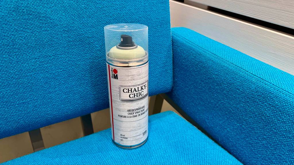 Eine Spraydose inklusive getestetem Kreidespray steht auf einem blauen Sessel.