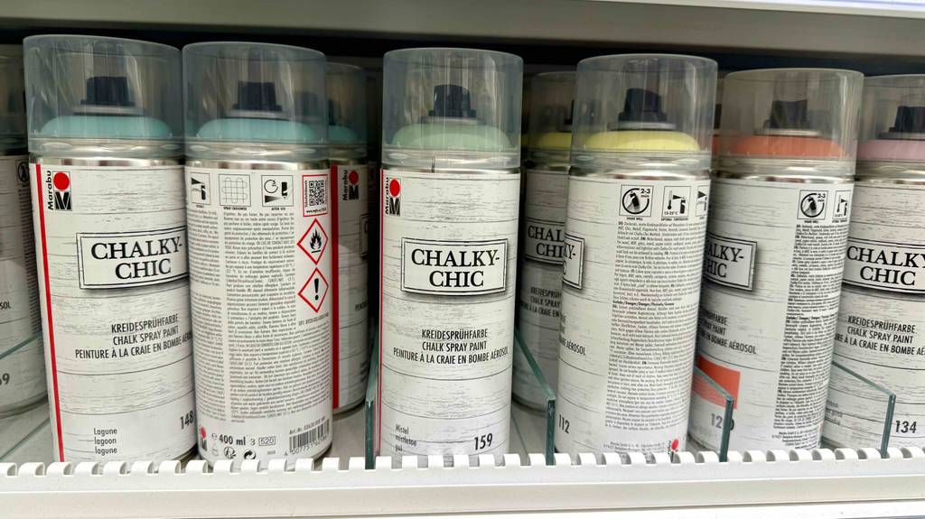 Kreidesprays im Test: Mehrere Spraydosen befinden sich nebeneinander in einem Verkaufsregal.