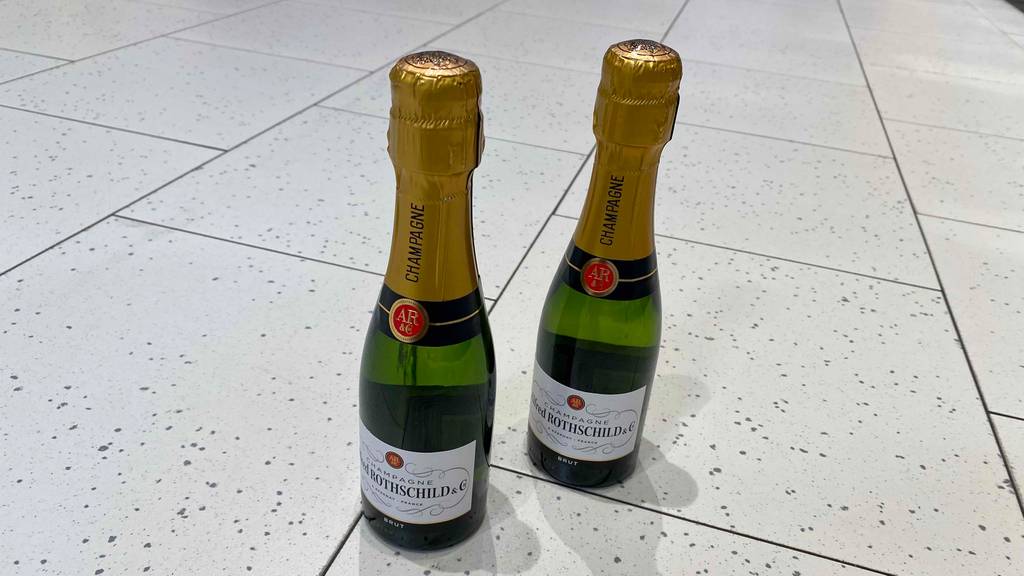 Zwei getestete Flaschen Champagner stehen auf dem Boden. 