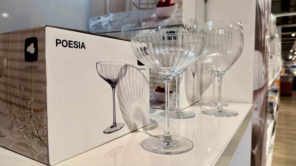 Auf einem weißen Verkaufsregal steht das getestete Champagnerglas in einem Laden.