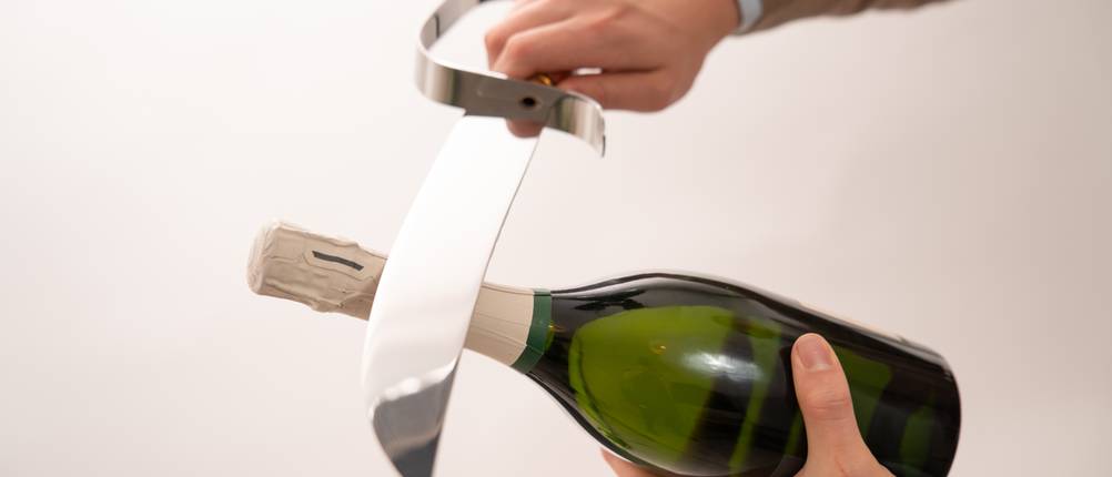 Champagnersäbel im Test: Ein Champagnersäbel wird an eine Flasche gehalten.