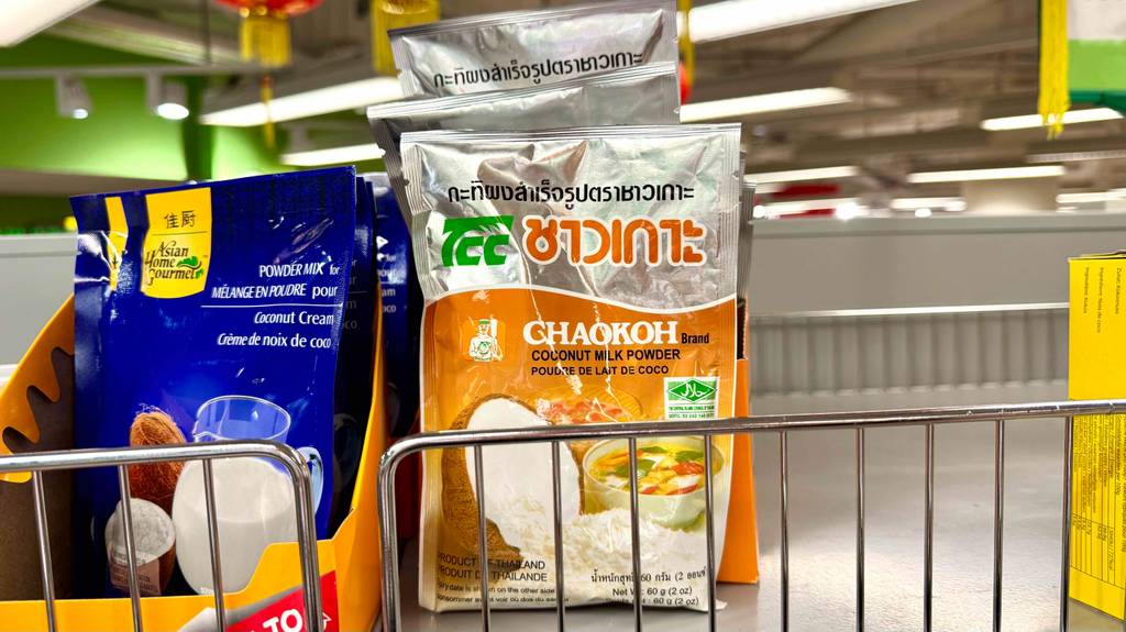 Kokosmilchpulver im Test: Mehrere Packungen stehen zwischen anderen Produkten in einem Regal.
