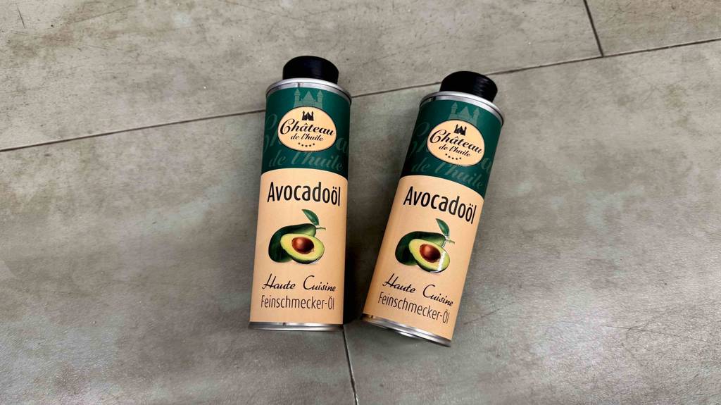 Zwei Dosen mit getestetem Avocadoöl liegen auf einem Fliesenbelag.