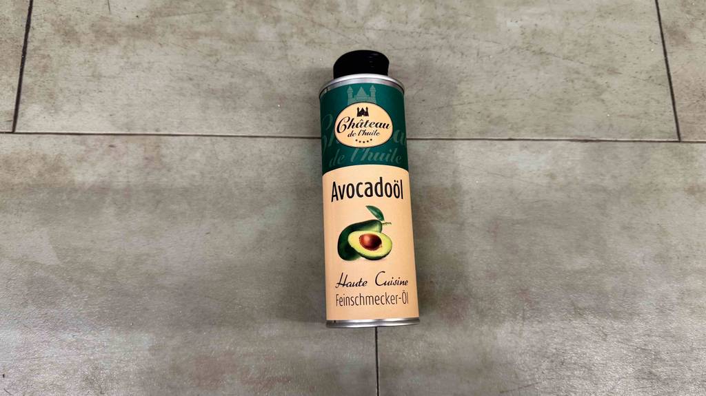 Ein Avocadoöl im Test befindet sich in einer Aluminiumdose auf einem grauen Bodenbelag.