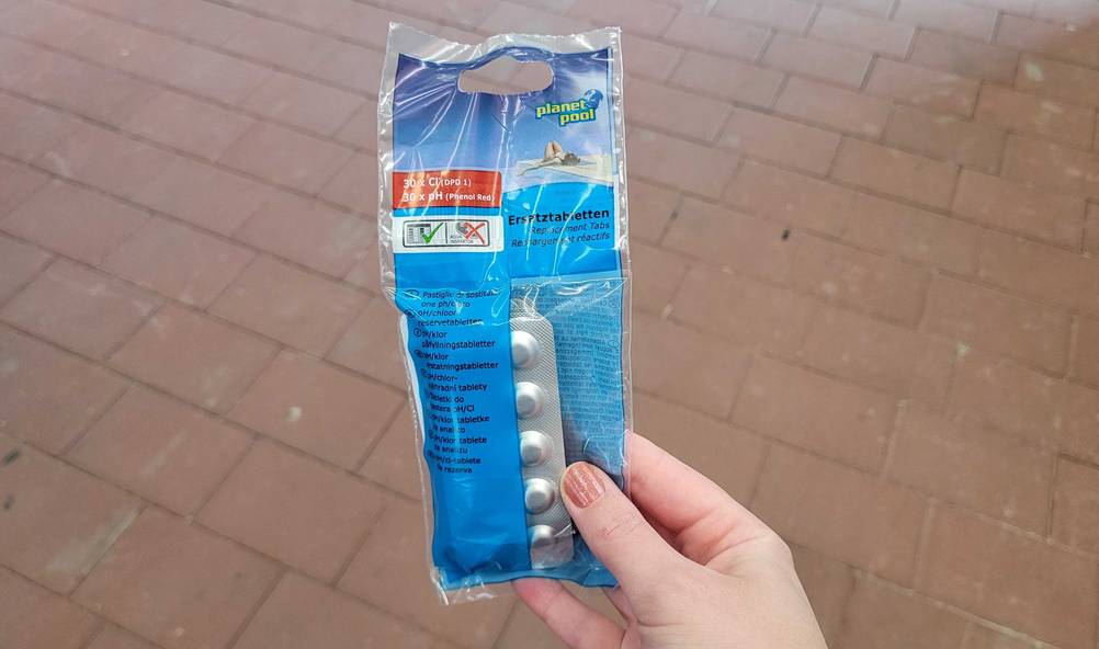 Eine Hand hält eine Packung der getesteten Chlortabletten (Pool).