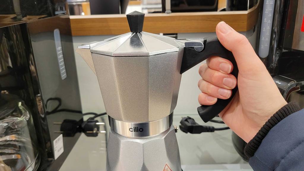 Im Test: Hand hält einen elektrischen Espressokocher mit Blick auf den oberen Teil des Geräts.