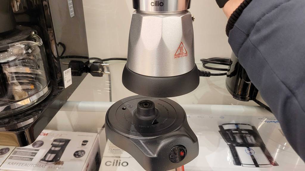 Ein Espressokocher elektrisch wird zum testen von seinem Sockel hochgehoben.
