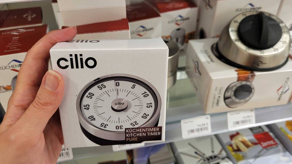 Eine Hand hält die Originalverpackung eines getesteten mechanischen Kurzzeitweckers von Cilio.