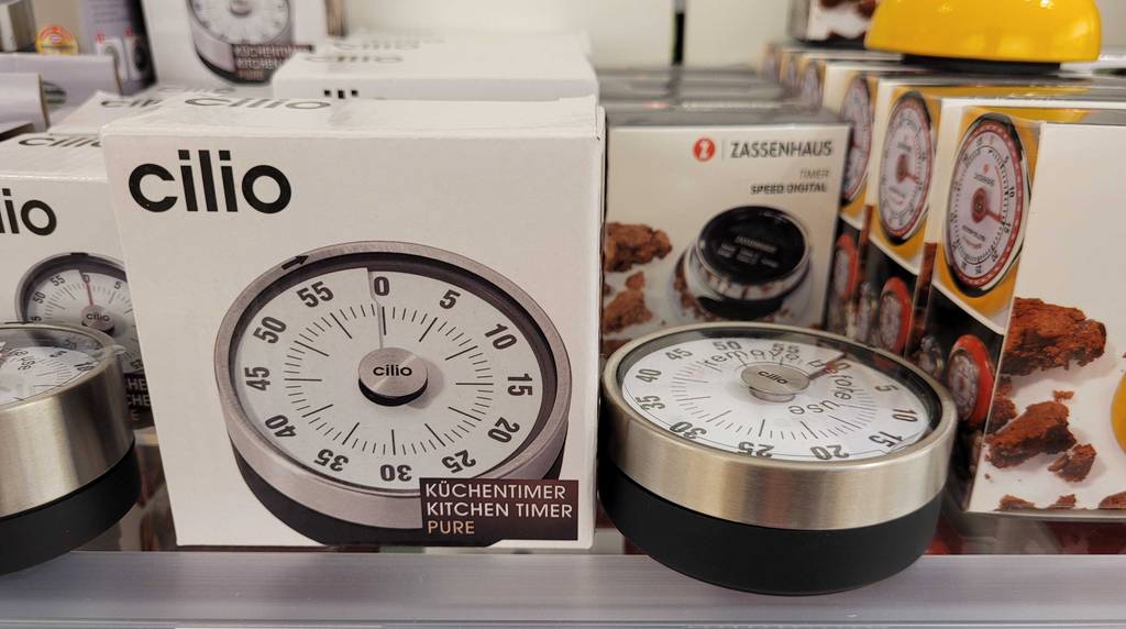 Seitenansicht eines getesteten Kurzzeitweckers mechanisch, der neben seiner Originalverpackung in einem Regal liegt.