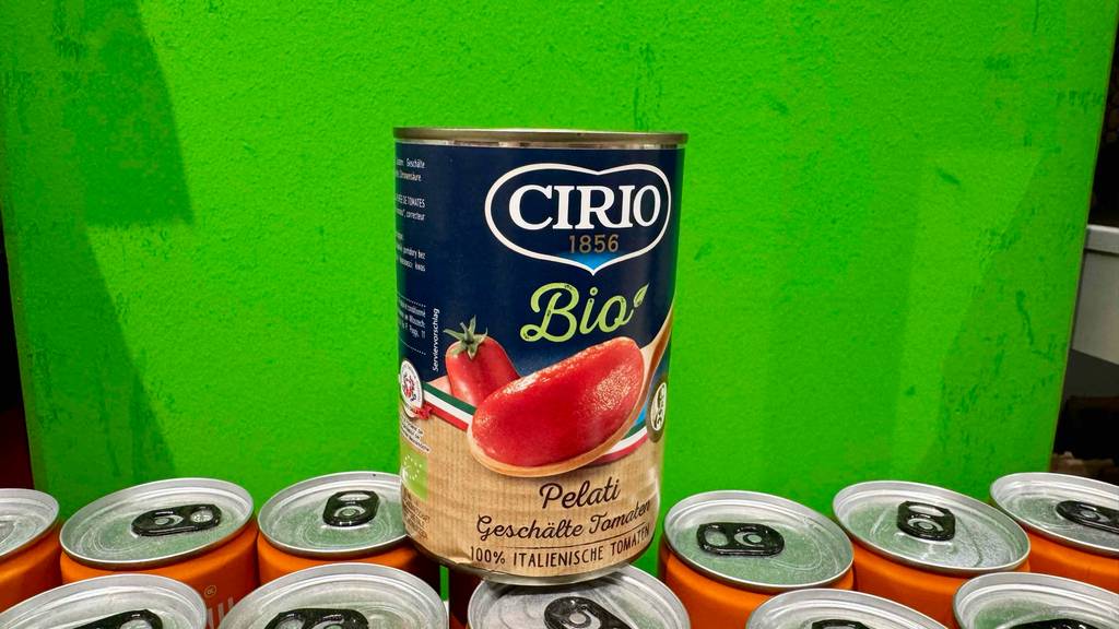 Getestet: Eine Dose Bio-Tomatensauce steht auf mehreren anderen Dosen vor einer grünen Wand.
