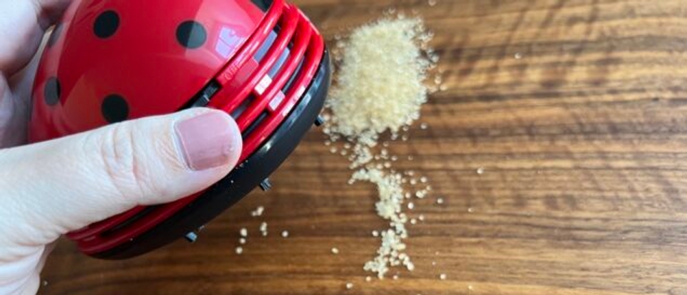Zucker wird vom Cisixin-Mini-Staub-Reiniger von einem Tisch aufgesaugt.