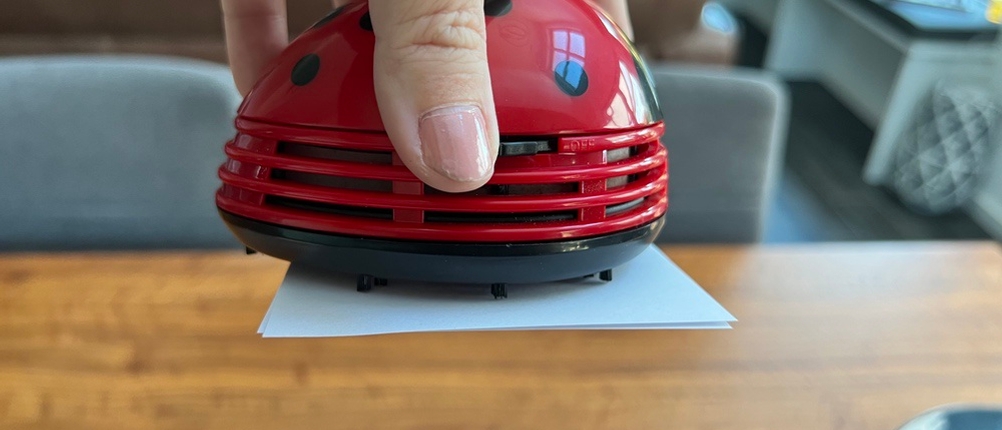 Cisixin-Mini-Staub-Reiniger hält zwei kleine Blätter Papier horizontal.