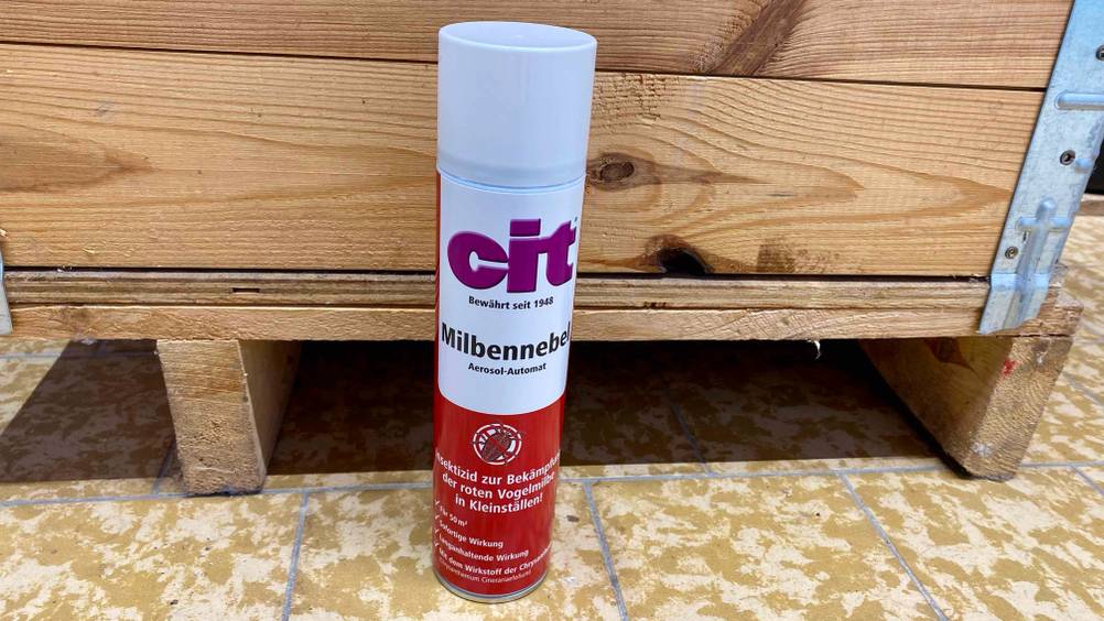 Milbenspray getestet: Eine Dose steht vor einer Holzbox auf einem Fließenboden.