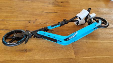 zusammengeklappter Cityroller in hellblau lieg auf dem Boden.