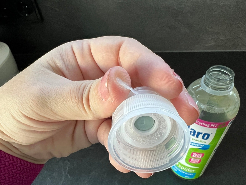 Eine Hand öffnet den Verschluss des Claro-Öko-Klarspülers