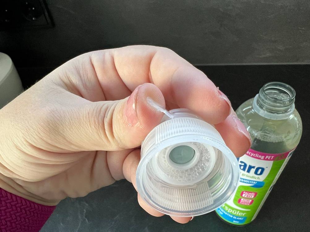 Eine Hand öffnet den Verschluss des Claro-Öko-Klarspülers