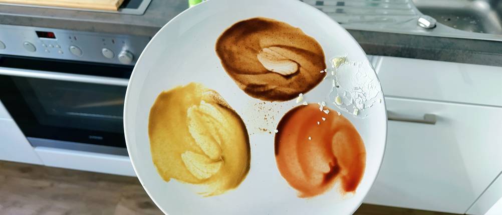 Ein mit Soßen verschmutzter Teller wird vor einer Spülmaschine hochgehoben.