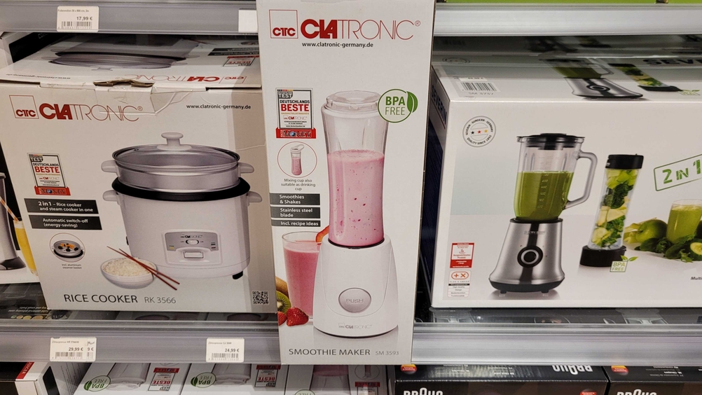 Smoothie-Maker-Test: Ein originalverpackter Smoothie-Maker von vorne zwischen anderen Produkten in einem Verkaufsregal mit Preisangaben.