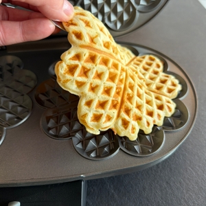 Eine Hand entfernt eine fertige Waffel aus dem Cloer 1329