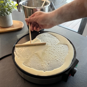 Eine Hand verteilt Teig auf dem Cloer 6630 mit dem Teigverteiler gleichmäßig