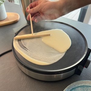 Eine Hand verteilt auf der Cloer 6630 mit dem Teigverteiler Teig