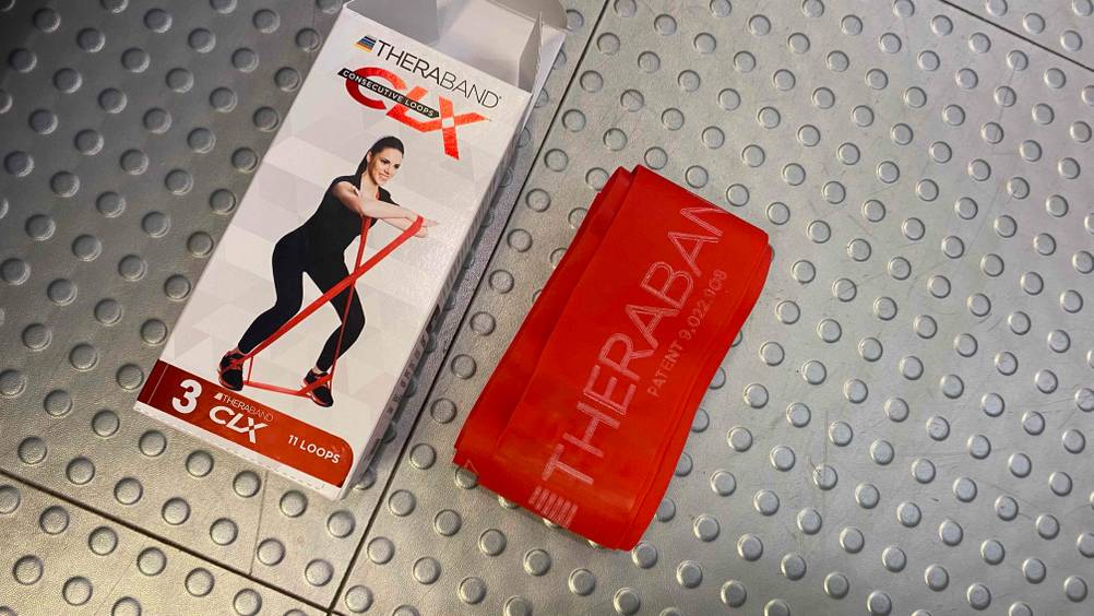 Im Test: Ein Thera-Band neben seiner Originalverpackung liegend auf einer Metallfläche.