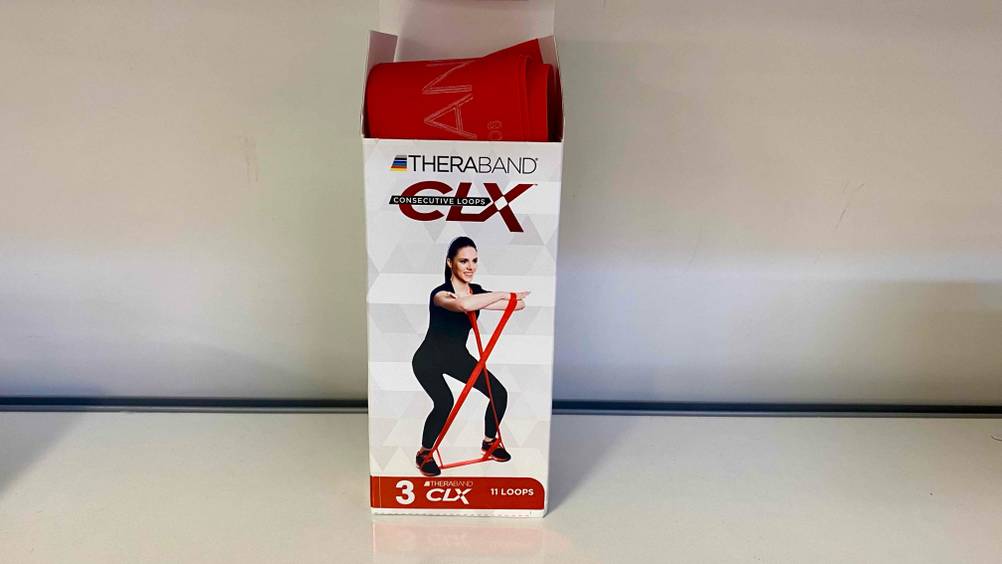Ein leicht aus der Verpackung schauendes Thera-Band im Test vor einer hellen Wand.