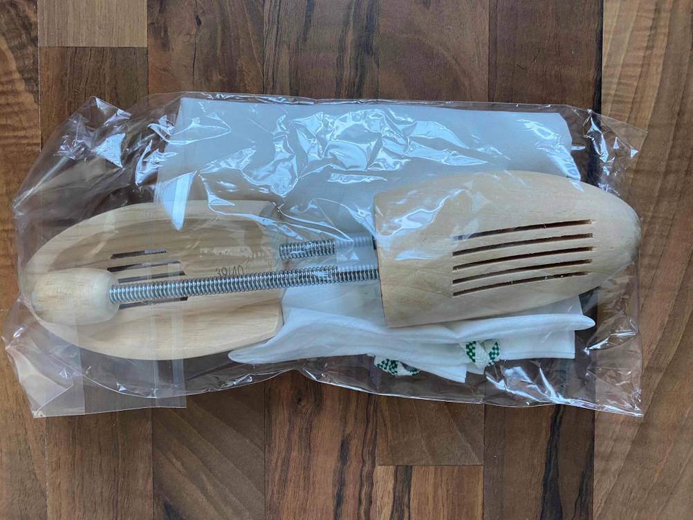 Auf einer Holzoberfläche liegen Stiefelspanner im Test in ihrer transparenten Originalverpackung.
