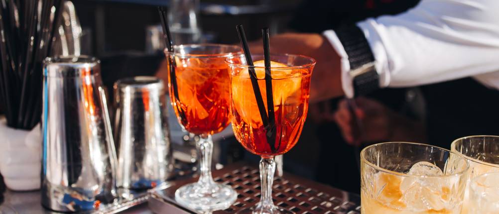 Cocktailgläser mit Aperol Spritz stehen auf einem Bar-Tresen.