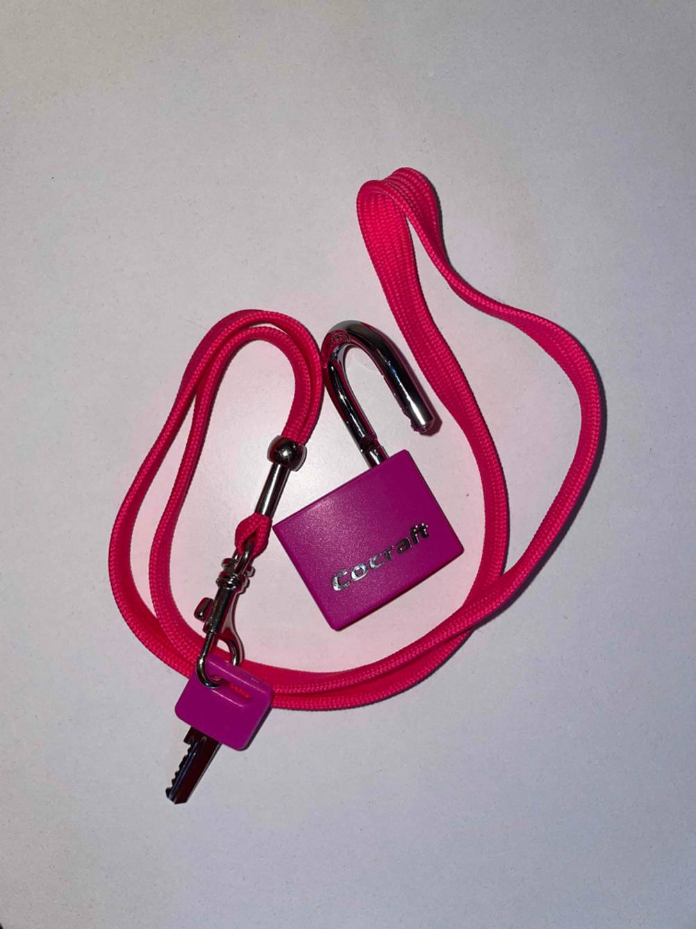 Geöffnetes Vorschängeschloss mit Schlüssel, der an einem Band befestigt wurde.