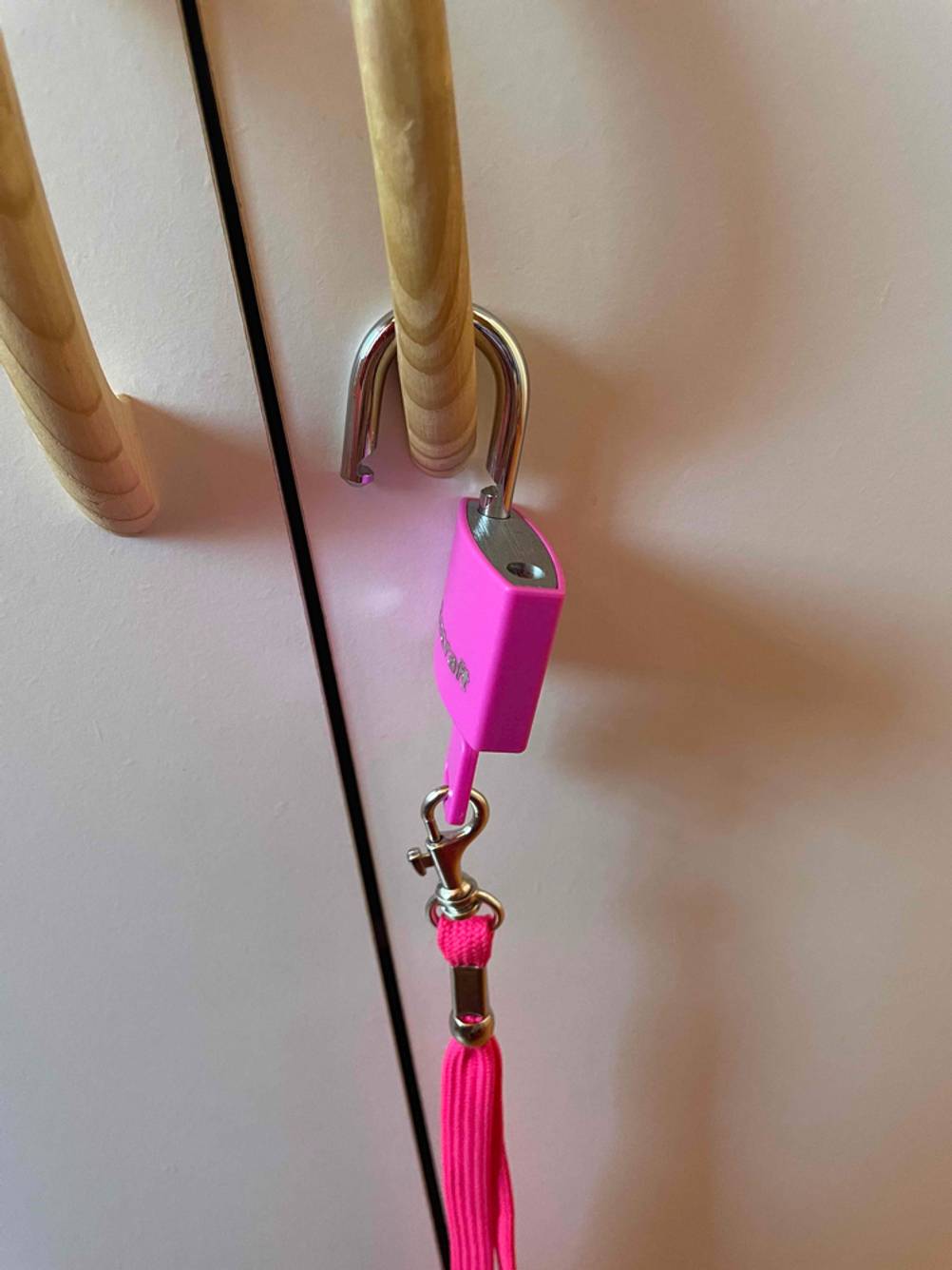 Geöffnetes Vorhängeschloss hängt an einer Tür.